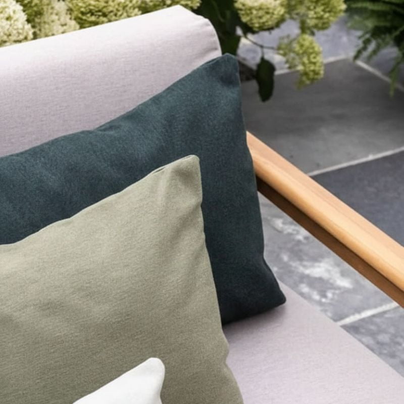 kompozycja gotowych poduszek na meblach zewnętrznych, wykorzystujących tkaniny Sunbrella Heritage w chłodnej palecie kolorów, z akcentami naturalnej zieleni