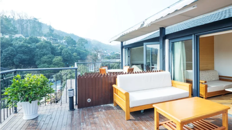 Jak ładnie i nowocześnie urządzić balkon? Jak urządzić duży balkon -Przestronny balkon z drewnianą podłogą i nowoczesnymi meblami wypoczynkowymi